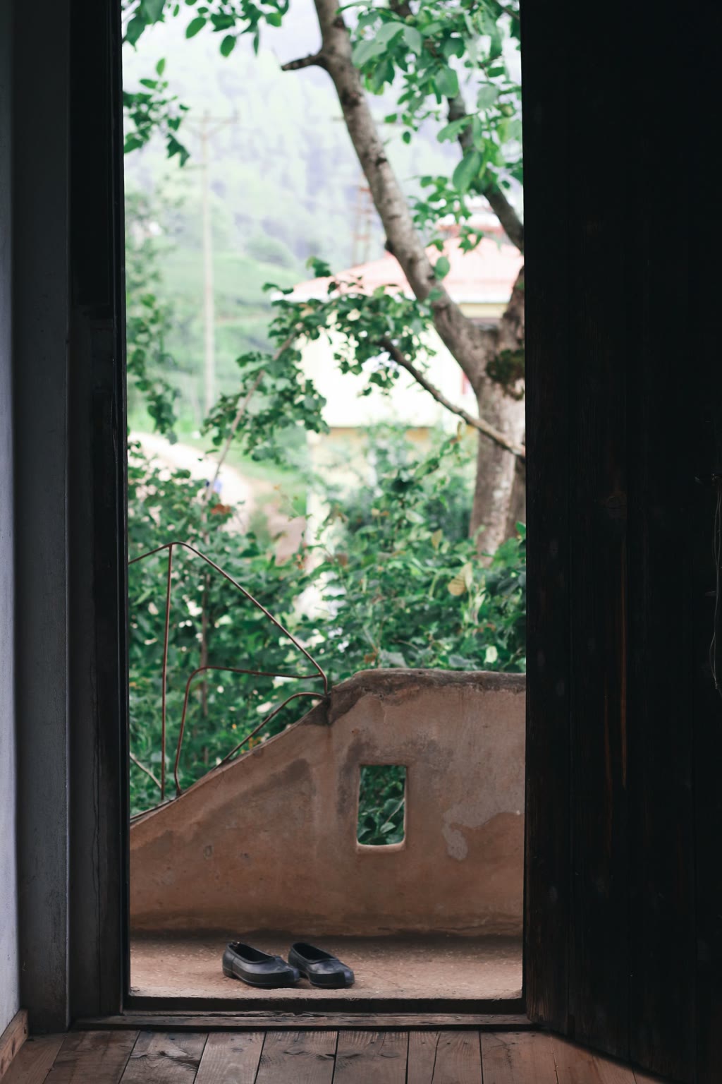 Shoes resting at an open doorway with a leafy garden beyond.